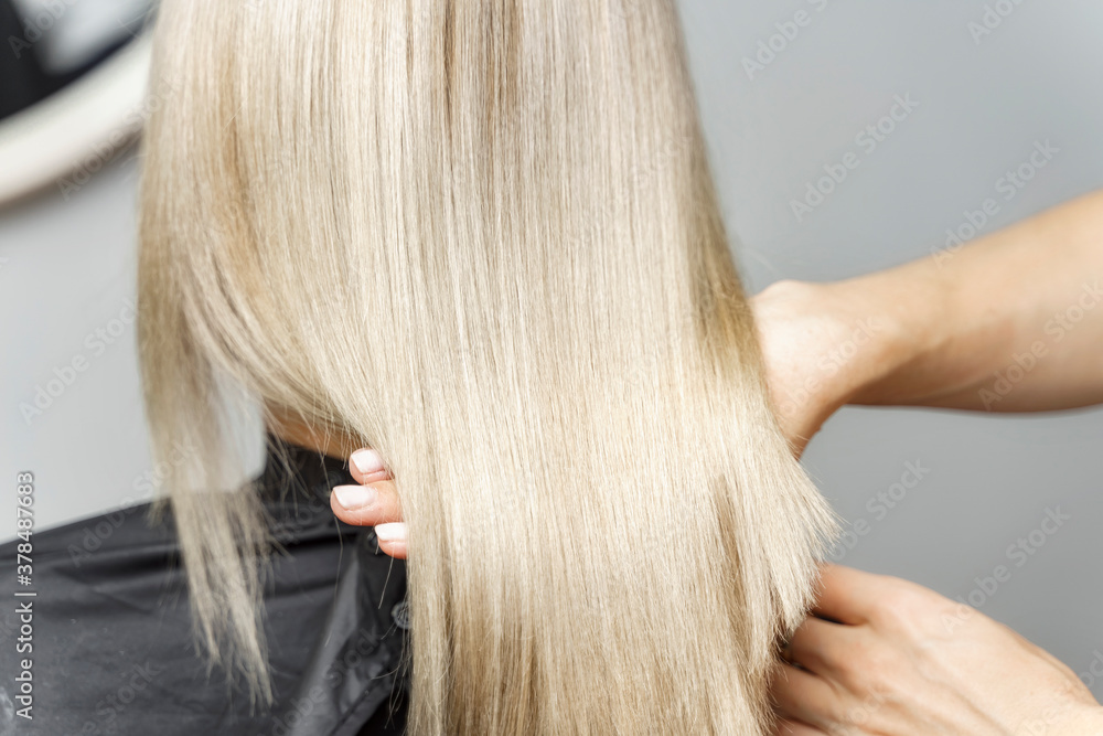 Fototapeta premium stylist calorist shows model's dyed blond hair