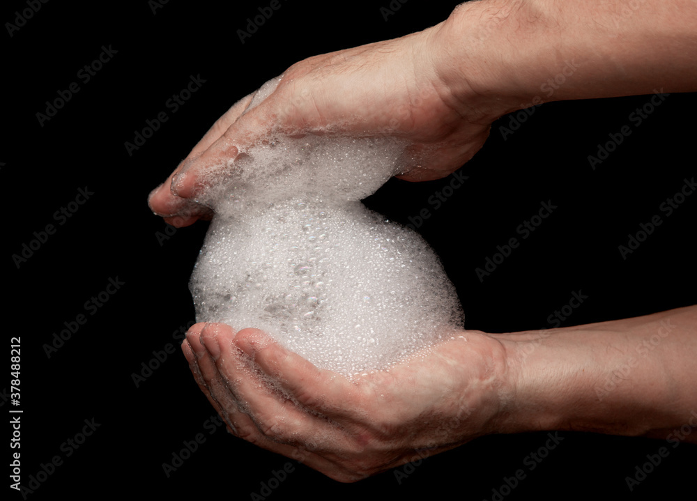 Naklejka premium hands in white foam from soap on a black background