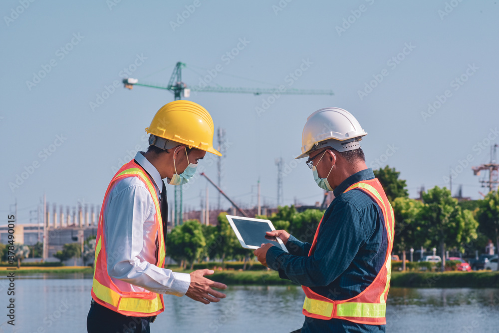 Businessman in medical mask talking on site construction by tablet technology