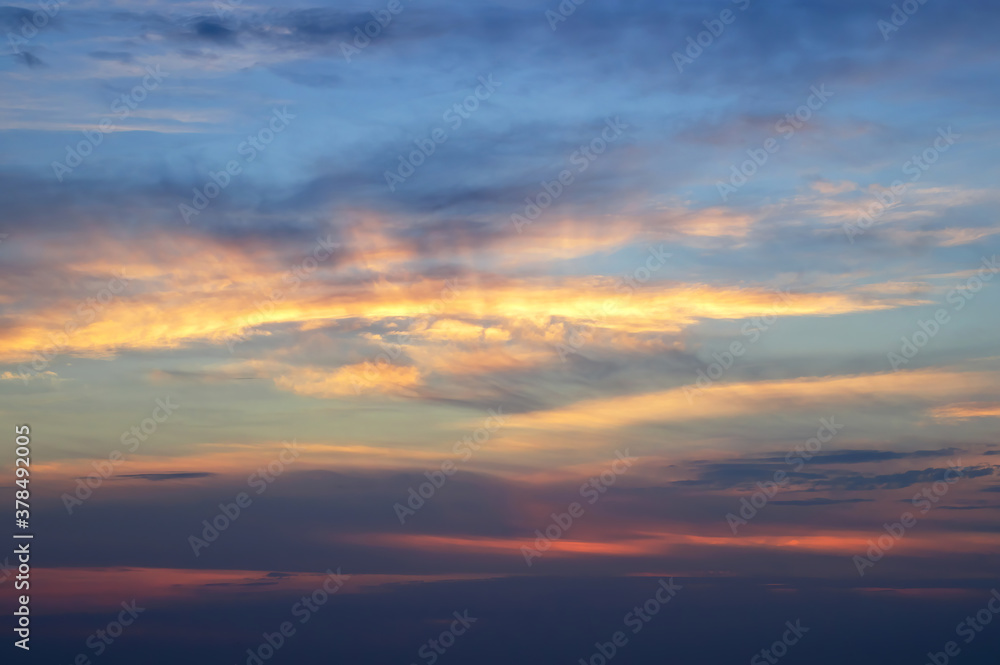 blurred beautiful multi-colored sky with clouds at sunset or sunrise. sun's rays color the clouds. Soft focus.