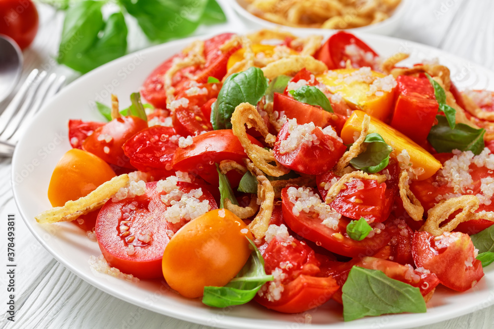 tomato salad with crispy fried onion, quinoa and fresh basil on a white plate on a wooden table, close-up, landscape view from above tomato salad with crispy fried onion, quinoa and fresh basil on a white plate on a wooden table, close-up, landscape view from above