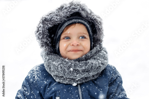 Portrait of cute baby boy in a warm white snow suit.