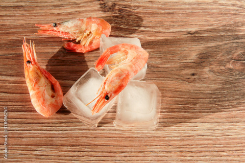 Frozen shrimp on ice on a wooden background.