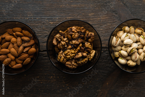 Almond, pistachio and walnut in a small plates which standing on a black table. Nuts is a healthy vegetarian protein and nutritious food.