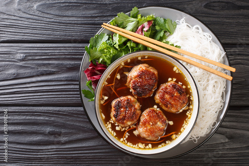 Bun cha is a delicious balance of noodles, a lot of herbs, a beautiful dressing and meatballs cooked over fire closeup in the plate on the table. Horizonta top view from above
