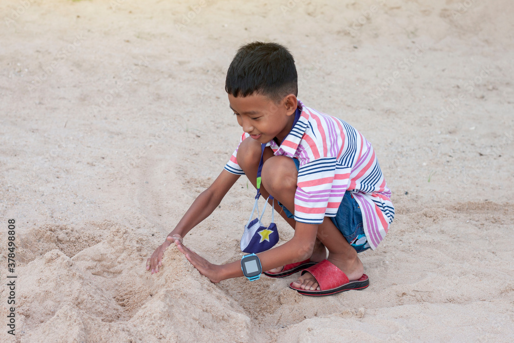 Asian boy playing with sand in a sandcastle shape on the summer beach. Asian boy playing with sand in a sandcastle shape on the summer beach.