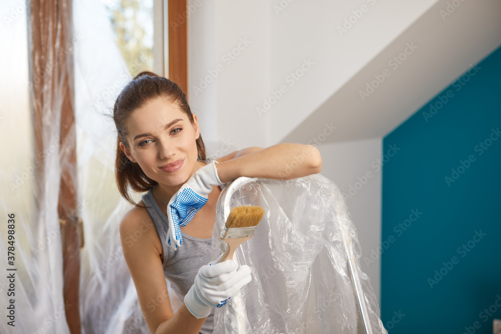 woman holding paint roller for wall painting and empty paint bucket with copy space isolated on background. Instruments for renovation apartment room. Repair home concept woman holding paint roller for wall painting and empty paint bucket with copy space isolated on background. Instruments for renovation apartment room. Repair home concept