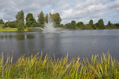 City Smiltene, Latvia.Fountain in the lake and around tree. photo