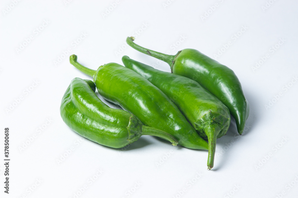 Green hot peppers on a white background. Several green hot peppers are lying next to each other. Healthy vegetables Green hot peppers on a white background. Several green hot peppers are lying next to each other. Healthy vegetables