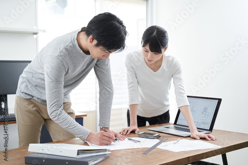 カジュアルなオフィスで打ち合わせをする日本人設計士