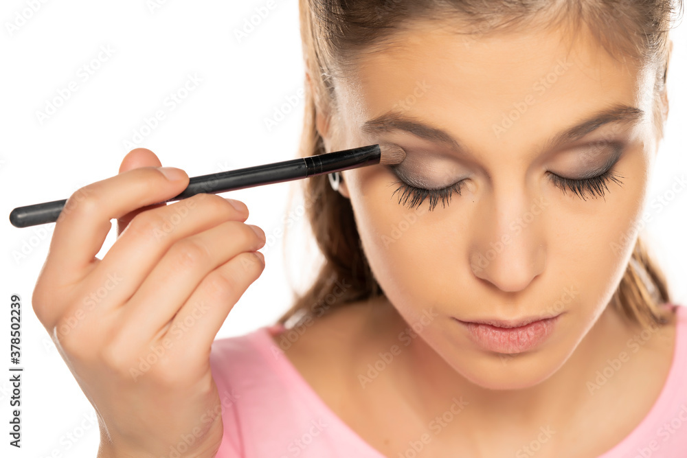 Portrait of young beautiful woman applying eyeshadow