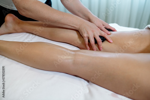 Massage therapist in a beauty salon giving a young woman a stone massage to relax the body and drain the lymph 