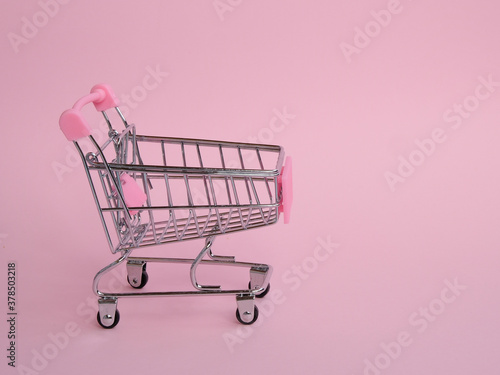 Small empty shopping cart on pink background