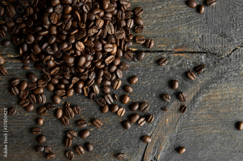 Roasted arabica coffee beans scattered on a wooden table. Fresh coffee beans.