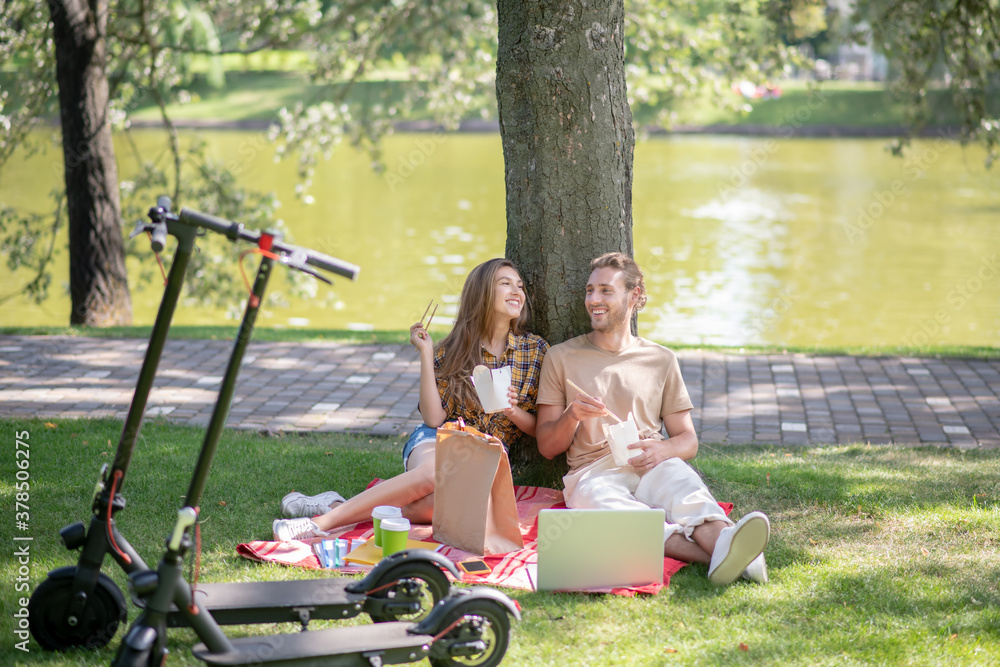 Young couple eating lunch in the park and looking peaceful Young couple eating lunch in the park and looking peaceful
