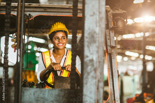 American black women labor worker at forklift driver happy working in industry factory logistic shipping warehouse. photo