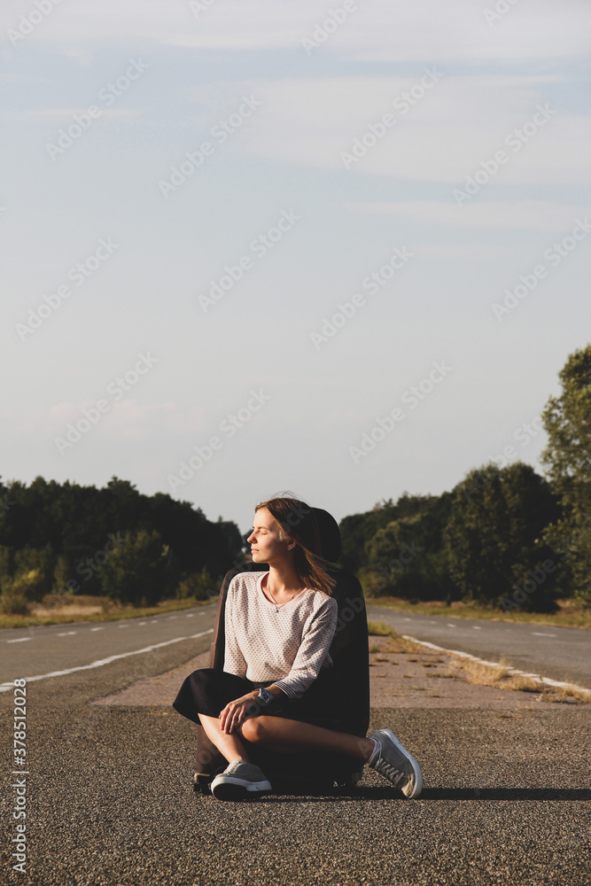 A beautiful girl sits on the background of the road and sky. Girl and nature A beautiful girl sits on the background of the road and sky. Girl and nature