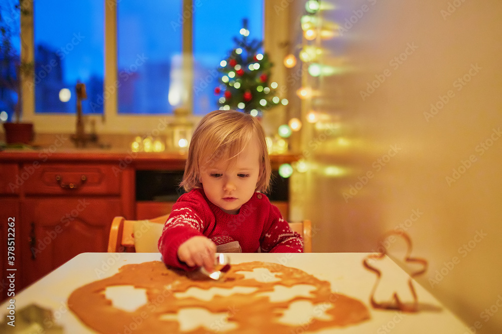 Adorable little toddler girl cooking Christmas cookies