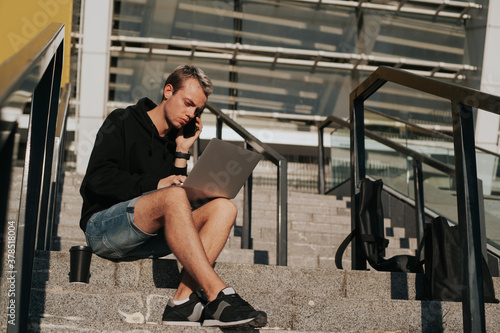 A man sits on the steps and works at a laptop until late at night