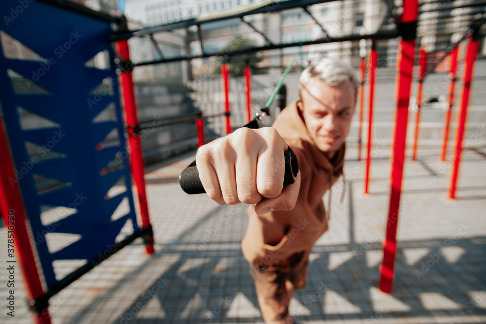 A man is training his hands on rubber loops. Healthy lifestyle of the athlete. Summer lifestyle is outdoor recreation A man is training his hands on rubber loops. Healthy lifestyle of the athlete. Summer lifestyle is outdoor recreation