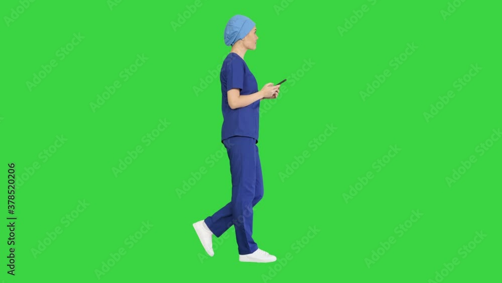 Female doctor or nurse in blue uniform using her phone as she walks on a Green Screen, Chroma Key. Female doctor or nurse in blue uniform using her phone as she walks on a Green Screen, Chroma Key.