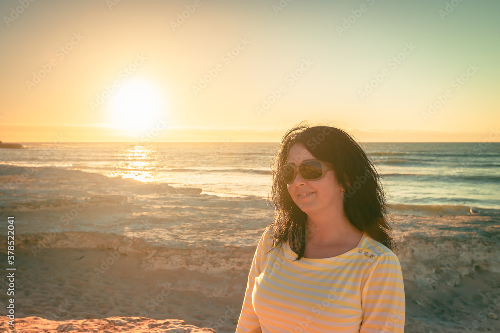 Woman sitting on beach and enjoying sunset at Port Noarlunga, South Australia Woman sitting on beach and enjoying sunset at Port Noarlunga, South Australia