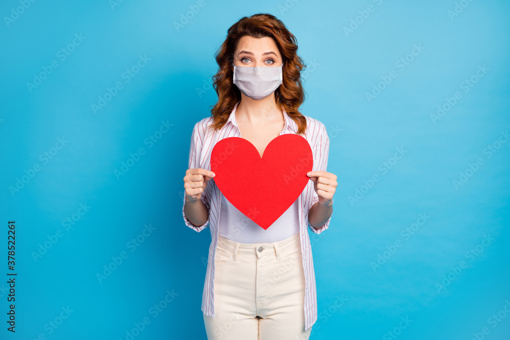 Portrait of her she nice pretty wavy-haired girl holding in hands big paper heart wear white medical mask care about stop covid infection spread isolated on shine blue color background Portrait of her she nice pretty wavy-haired girl holding in hands big paper heart wear white medical mask care about stop covid infection spread isolated on shine blue color background