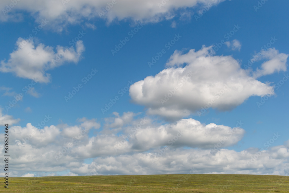 white bright fluffy clouds in blue sky with green grass field, open space white bright fluffy clouds in blue sky with green grass field, open space