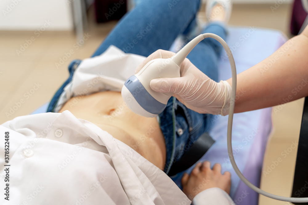 Pregnant woman getting ultrasound from doctor. Ultrasound equipment in clinic. Selective focus on belly. Pregnant woman getting ultrasound from doctor. Ultrasound equipment in clinic. Selective focus on belly.