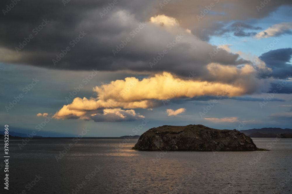 evening bright yellow orange sunset with clouds on lake baikal with island and mountains