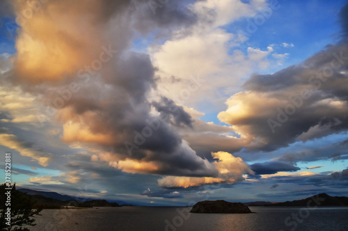 evening bright yellow orange sunset with clouds on lake baikal with islands and mountains