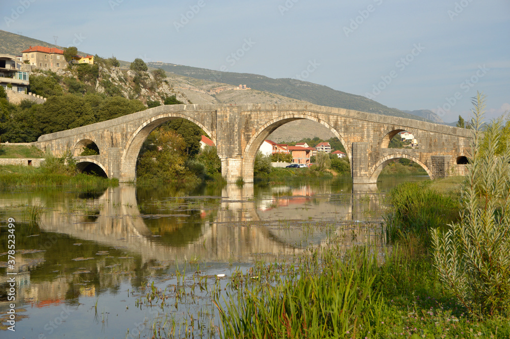 old stone bridge with arches in Trebinje in the sun light with blue sky, Bosnia and Herzegovina