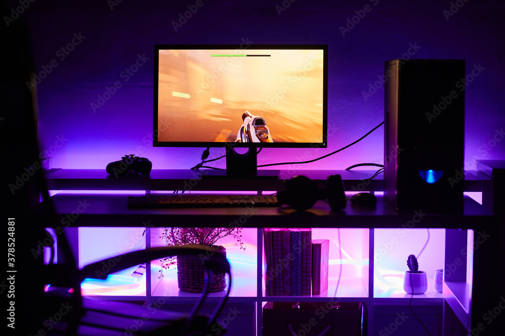 Image of computer monitor with game on it on the table with bright light in dark room Image of computer monitor with game on it on the table with bright light in dark room