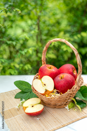 Fresh Apple fruits in Bamboo basket on wooden table in garden, Apples group freshly picked in a basket on a wooden table.