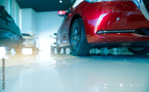 Blurred red and white car parked in modern showroom. Car dealership and auto leasing concept. Automotive industry. Modern luxury showroom. New car global market trends topics background. © Artinun