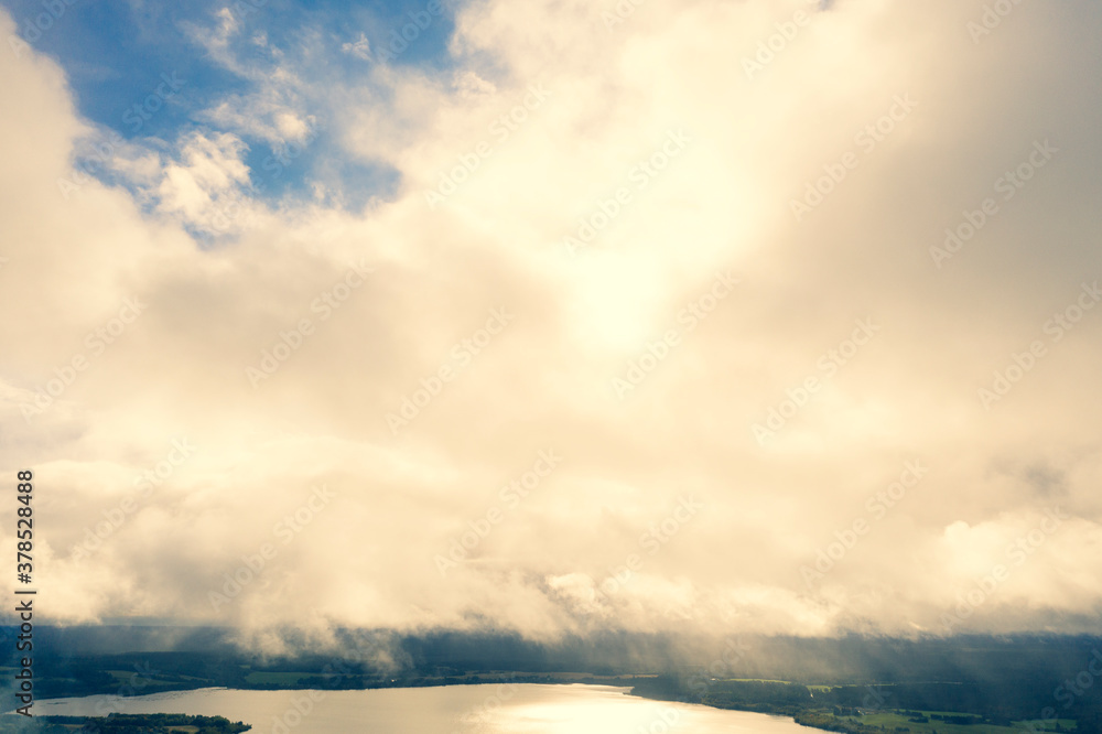 Obraz premium Aerial view clouds over the forest and lake. View from drone. Aerial top view cloudscape. Texture of clouds. View green forest from above covered with white clouds