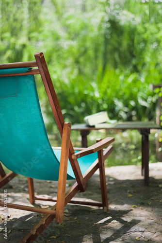 Wooden beach chair in the garden and some books on the table. Relaxing place concept.