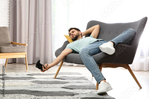Lazy young man playing video game while lying on sofa at home photo