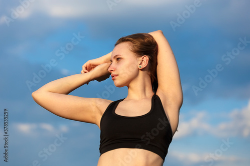 Young girl teenager wearing sportswear over blue sky background with hands together over her head © bander