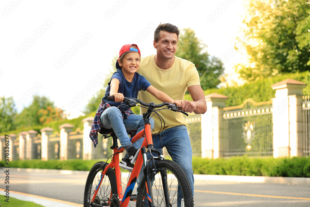 Dad teaching son to ride bicycle outdoors Dad teaching son to ride bicycle outdoors