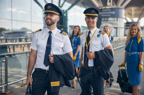 Foto Cheerful pilots and stewardesses standing on the street