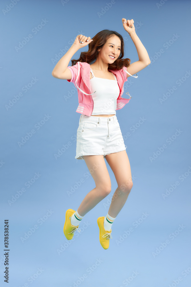 Cheerful hipster girl jumpig with hands spread wide over background. Young woman in jump. Cheerful hipster girl jumpig with hands spread wide over background. Young woman in jump.