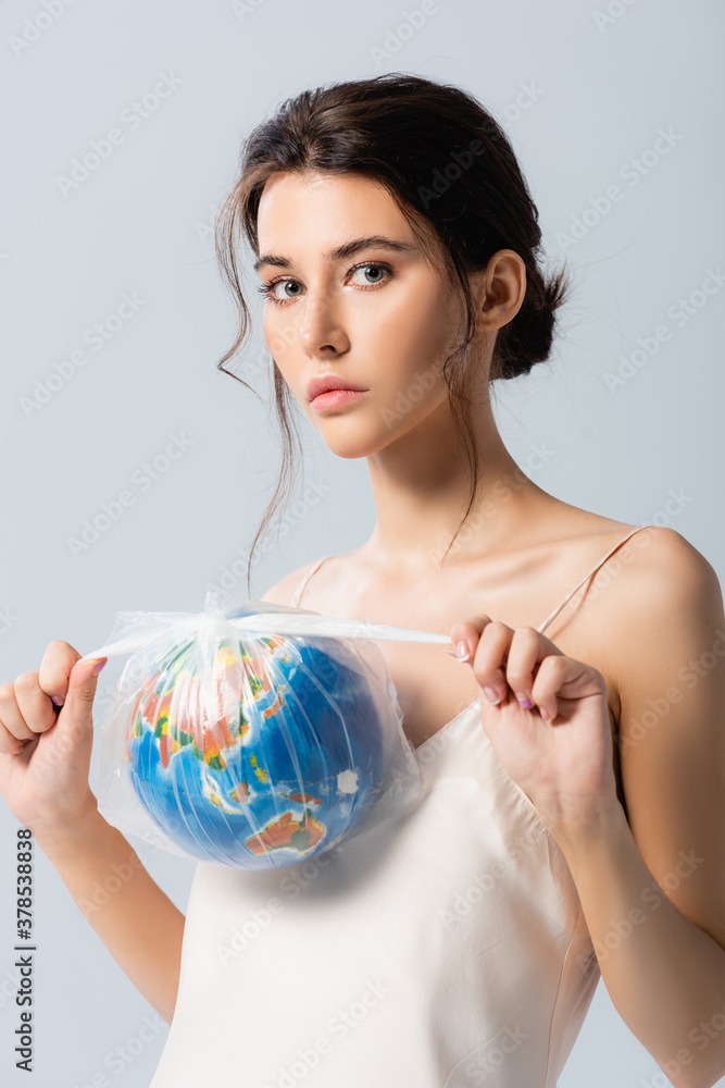 young brunette woman holding plastic bag with globe and looking at camera isolated on white, ecology concept young brunette woman holding plastic bag with globe and looking at camera isolated on white, ecology concept