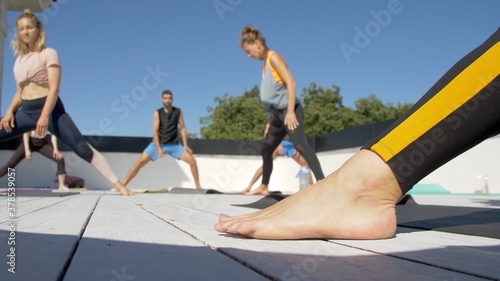 Group of adults peoples doing yoga outdoors on the roof of the house. Outdoor group yoga classes back view. Many people 