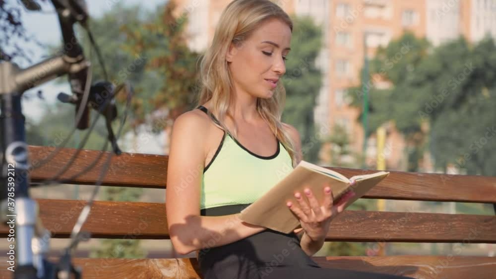 Happy athlete woman reading a book sitting on a bench outdoors Happy athlete woman reading a book sitting on a bench outdoors