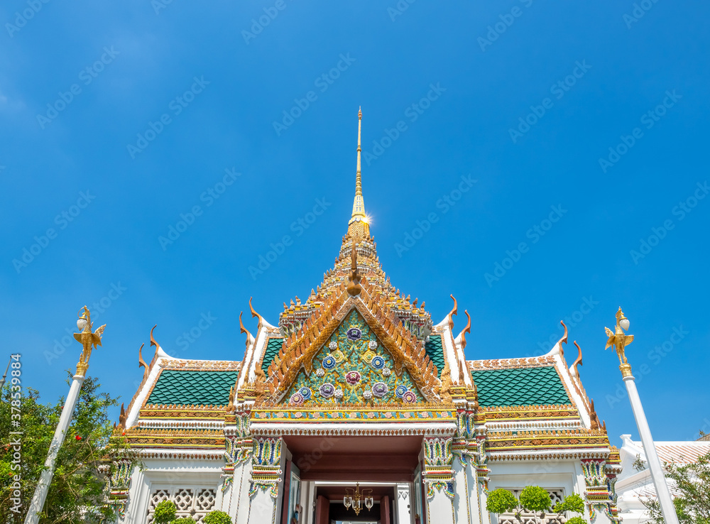 Art at facade and entrance door in The Temple of Emerald Buddha, the most beautiful landmark in Bangkok, Thailand, under summer blue sky