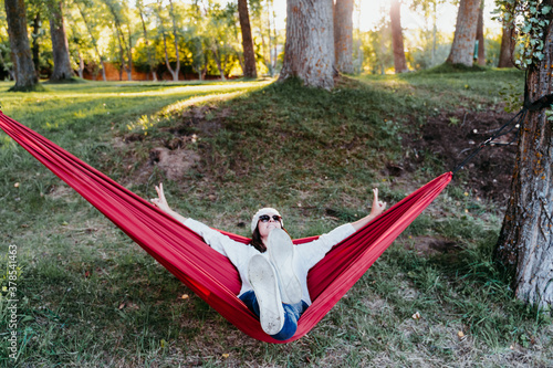 happy woman relaxing in orange hammock. Camping outdoors. autumn season at sunset