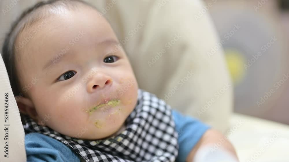 Asian 8 months baby boy eating blend food on a high chair, Mother feeds a Little Baby with a Spoonful of food. Asian 8 months baby boy eating blend food on a high chair, Mother feeds a Little Baby with a Spoonful of food.