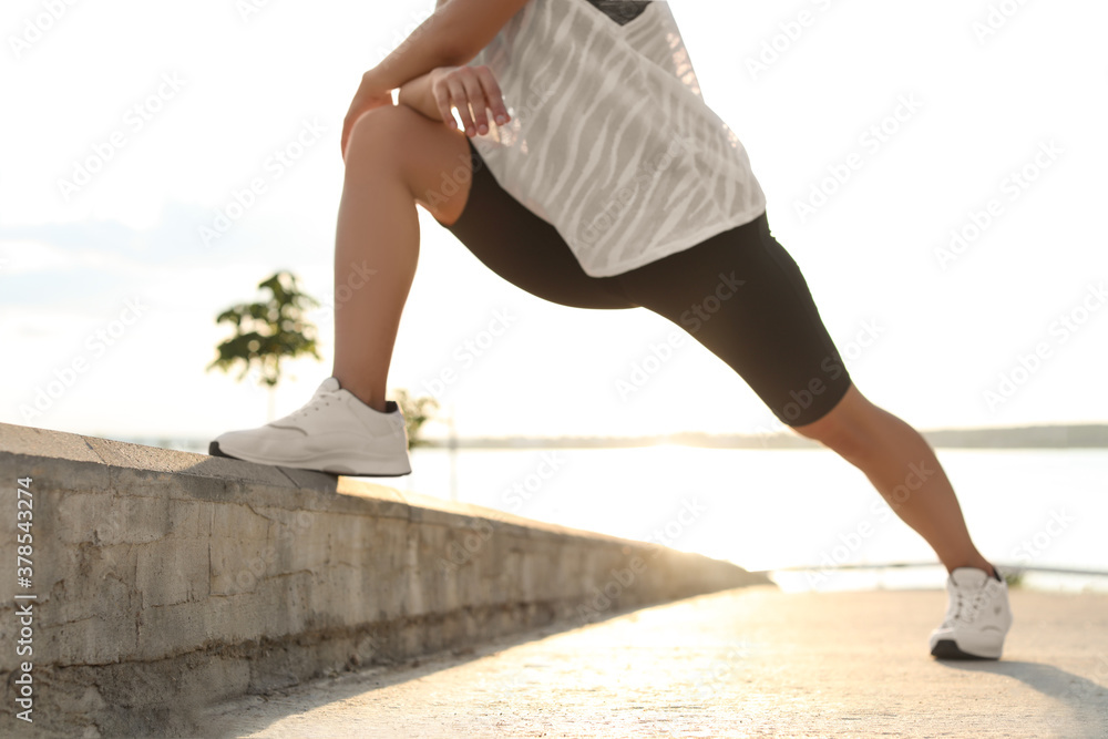 Young woman stretching outdoors in morning, closeup Young woman stretching outdoors in morning, closeup