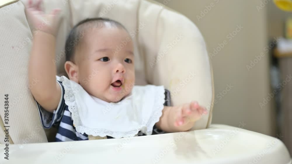 Asian 8 months baby boy eating blend food on a high chair, Mother feeds a Little Baby with a Spoonful of food. Asian 8 months baby boy eating blend food on a high chair, Mother feeds a Little Baby with a Spoonful of food.
